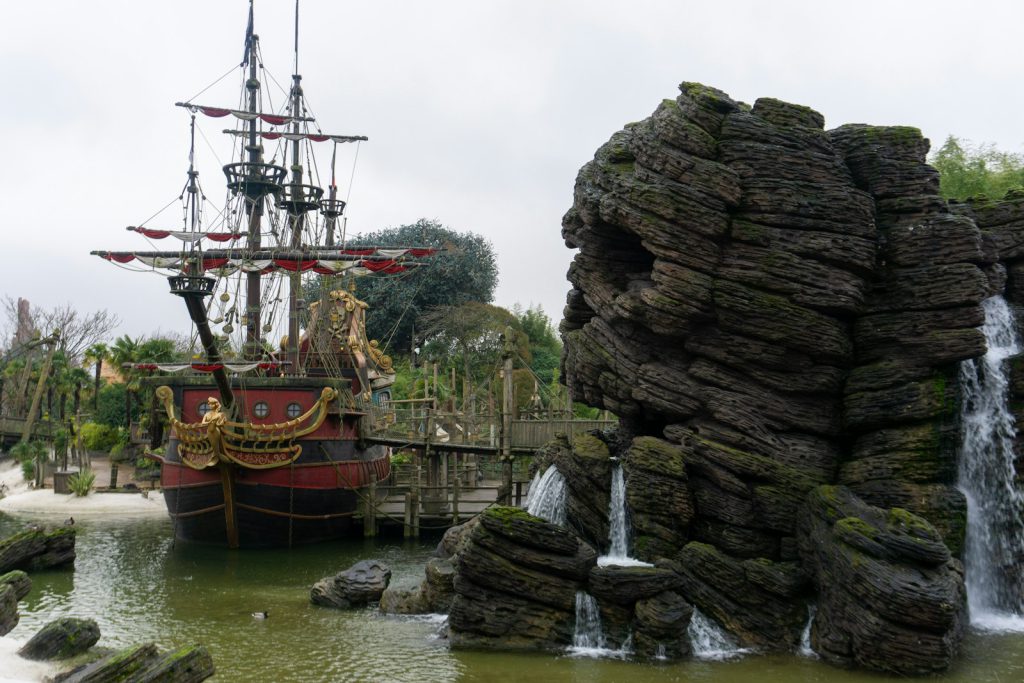a pirate ship in the water near a waterfall