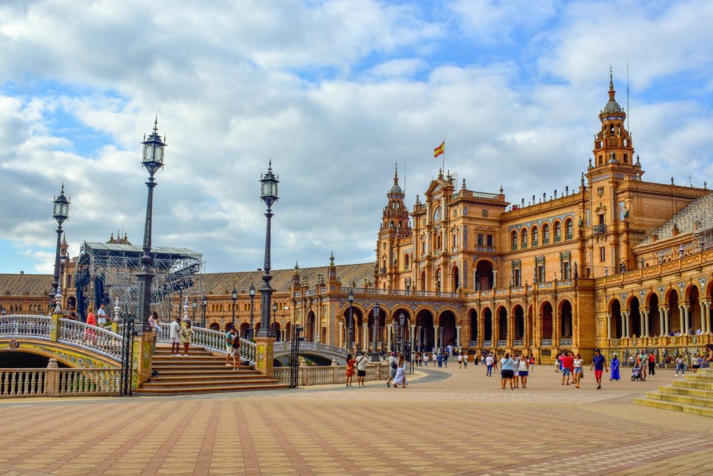 A large building with a lot of people walking around it Photo by Alex Sevilla