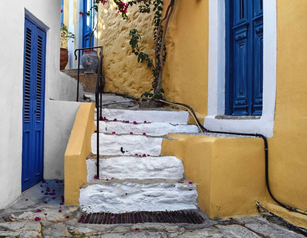 Colorful stone steps and blue doors in Ano Symi, Greece, showcasing old town charm.